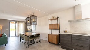 Una cocina moderna con comedor, armarios de madera e iluminación colgante.