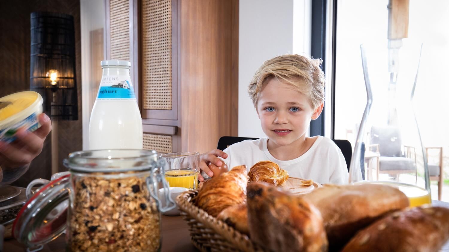 Une table mise pour le petit-déjeuner avec une bouteille de lait, un verre de jus d’orange et diverses pâtisseries.