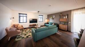 Una sala de estar moderna con un sofá, sillones, una mesa de centro y un televisor.
