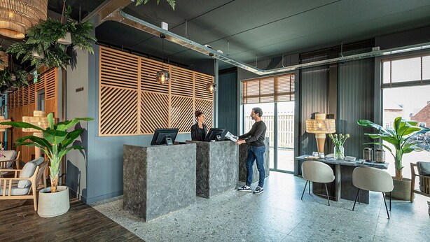 A reception area with a modern design, featuring a reception desk, seating area, and large windows.