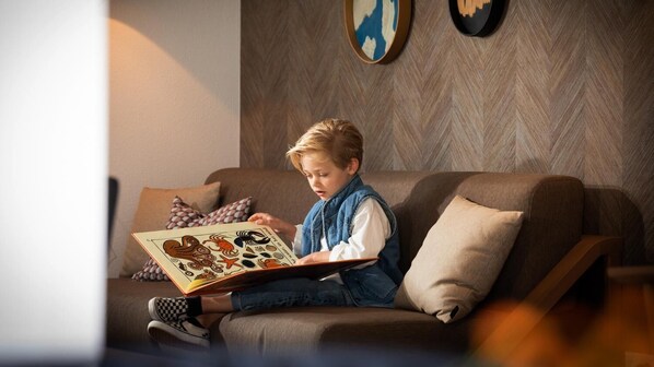 Un enfant assis sur un canapé, en train de lire un livre.