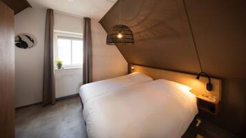A bedroom with a bed, a window, a wall-mounted lamp, and a ceiling light.