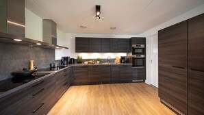 Una cocina moderna con armarios de madera oscura, una isla central y electrodomésticos integrados.