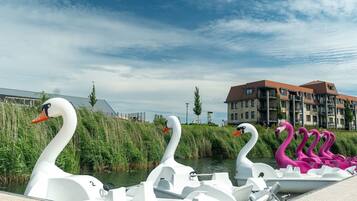 Una hilera de barcas con forma de cisne a lo largo de un canal, con un edificio al fondo.