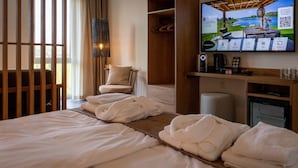 A hotel room with a bed, a chair, a TV, and a desk with a computer and a lamp. - Lake View Hotel Room 2p (Thorn)