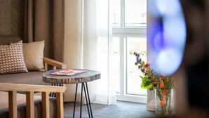 A cozy room with a sofa, a small round table, and a vase with flowers. - Lake View Hotel Room 2p (Thorn)