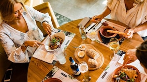 A group of people dining at a wooden table with menus, bread, and a bottle of beer. - Lake View Hotel Room 2p (Thorn)