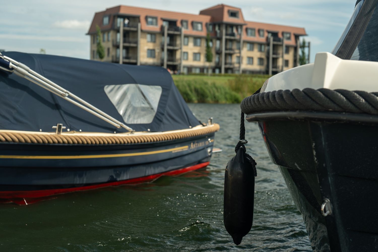 A boat docked near a building with multiple balconies.
