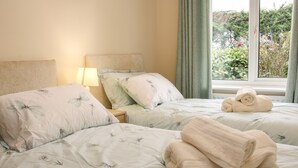 Una habitación de hotel con dos camas, cada una con ropa de cama floral y una mesita de noche con lámpara.