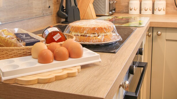 Una encimera de cocina con un pastel, huevos, galletas con chispas de chocolate y un tostador.