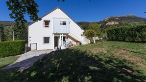 Et toetagers hvidt hus med en fordør, en lille veranda og en trappe op til anden sal.