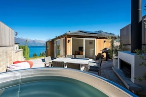 A pool area with a hot tub, outdoor seating, and a view of the sea.
