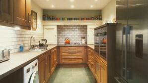 Een moderne keuken met houten kastjes, een roestvrijstalen koelkast, een inbouwoven en een waterkoker op het aanrecht.