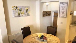 Un comedor con una mesa redonda, sillas y un panel con la carta en la pared.