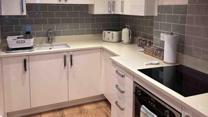 Una cocina moderna con armarios blancos, una estufa negra y un salpicadero de azulejos.