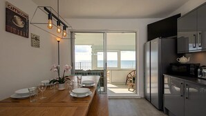 Een moderne keuken met een houten eettafel, uitzicht op zee en een balkon.