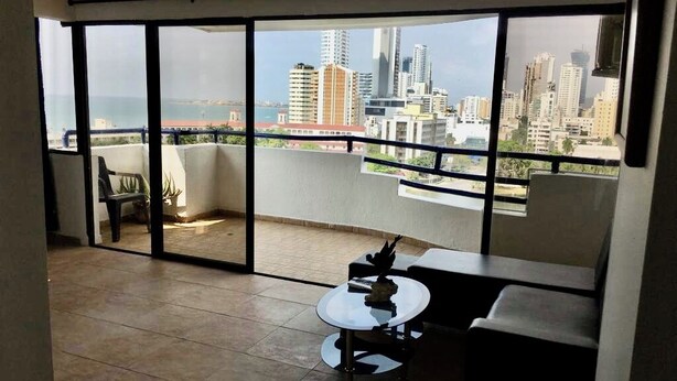 Un balcón con vistas a un horizonte urbano y al mar.