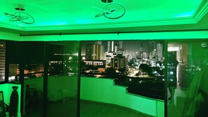 Habitación con vista a la ciudad, ventilador de techo y balcón con barandilla.