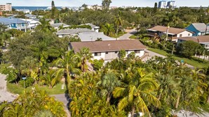 Un quartiere residenziale con case circondate da vegetazione lussureggiante e palme.