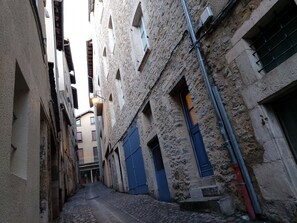 A narrow alleyway with stone buildings, blue doors, and visible pipes. - Le Petit Saint-Georges 2*: a renovated, fully equipped studio at the foot of the Collegiate Church (Villefranche-de-Rouergue)