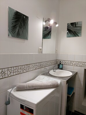 A bathroom with a white washing machine, a sink, and a mirror. - Le Petit Saint-Georges 2*: a renovated, fully equipped studio at the foot of the Collegiate Church (Villefranche-de-Rouergue)