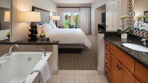 Ein Hotelzimmer mit einem großen Bett, einem eigenen Badezimmer mit einer Badewanne, einem Schminktisch mit Waschbecken und Blick ins Freie.
