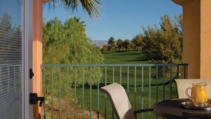 Ein Balkon mit Blick auf einen Golfplatz, ein Tisch mit einer Kanne Orangensaft und ein Stuhl.