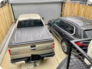 Ein Pickup-Truck parkt in einer Garage mit Holzzaun und geschlossener Garagentür im Hintergrund.