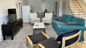 A modern living room with a sofa, armchairs, a coffee table, and a TV on a cabinet. - New 2 BR APT: amazing location, spotless, free private parking.  (Washington)