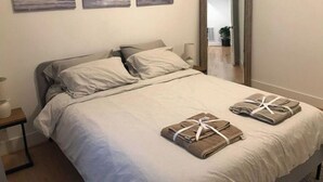A bedroom with a bed, pillows, a bedside table, a lamp, and artwork on the wall. - New 2 BR APT: amazing location, spotless, free private parking.  (Washington)