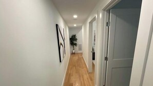 A hallway with wooden flooring, white walls, and a door on the right. - New 2 BR APT: amazing location, spotless, free private parking.  (Washington)
