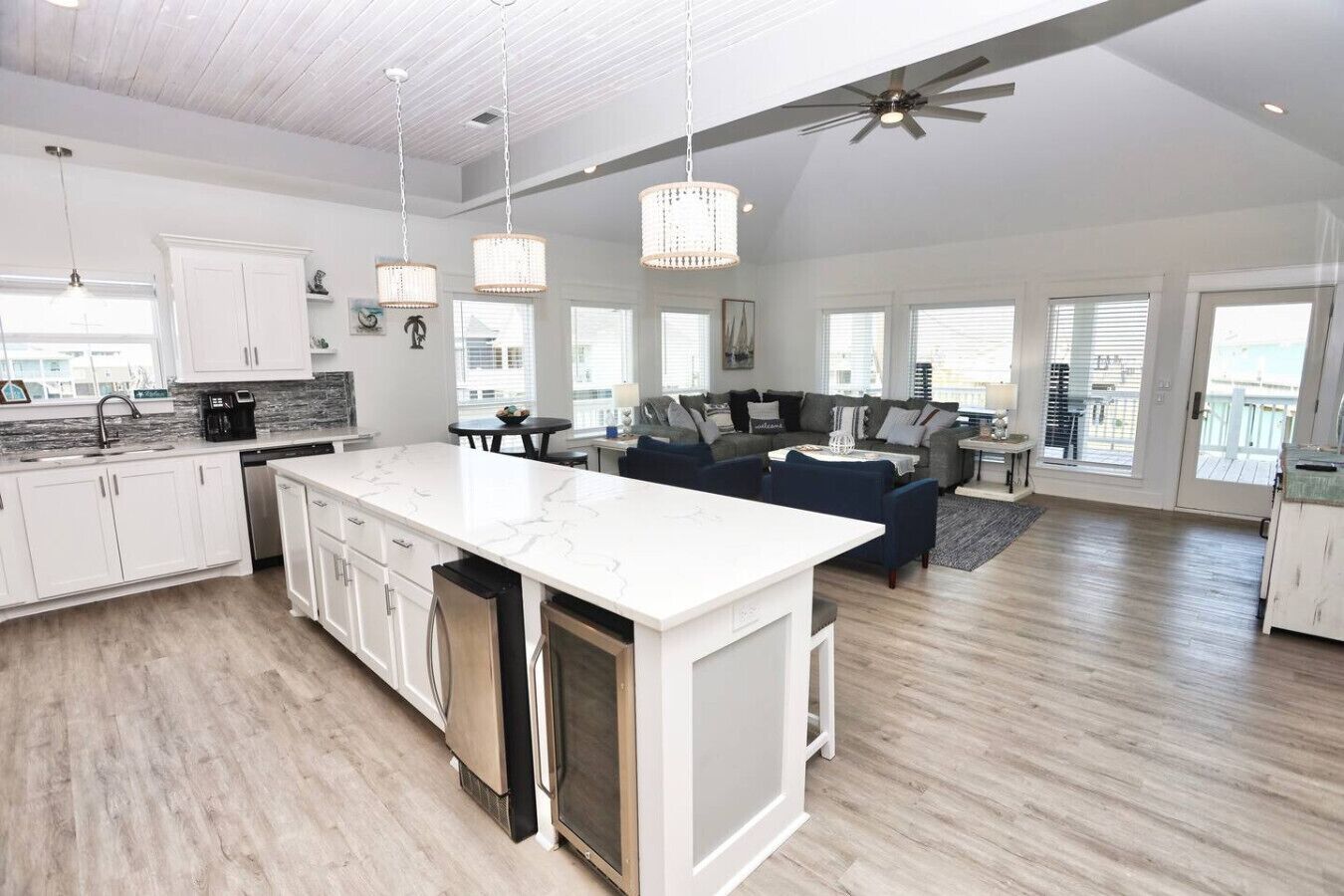 A spacious kitchen with a large island, white cabinetry, and a ceiling fan.