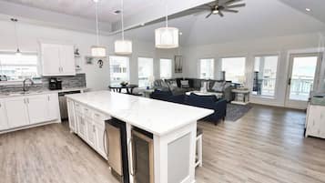 A spacious kitchen with a large island, white cabinetry, and a ceiling fan.