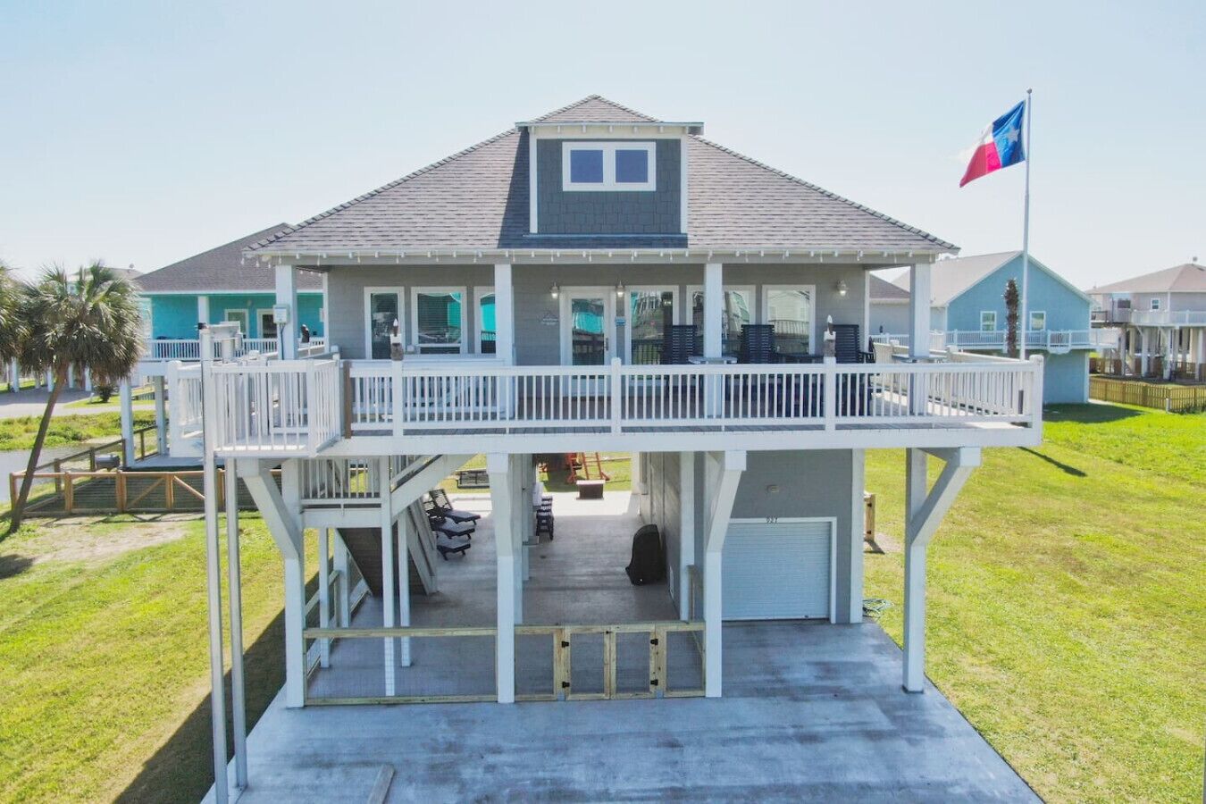 A two-story house with a balcony, a garage, and a flag.