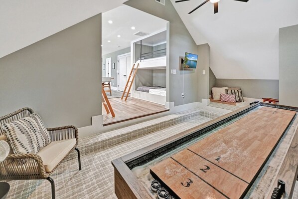A room with a pool table, a wicker chair, and a view of a bedroom with a ladder. - Channel Marker: Exclusive Lakefront Home w/Hot Tub, Custom Bunk Room, Dock & Optional Boat Rental (Mooresville)