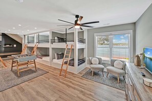 A modern interior with bunk beds, a foosball table, and a TV. - Channel Marker: Exclusive Lakefront Home w/Hot Tub, Custom Bunk Room, Dock & Optional Boat Rental (Mooresville)