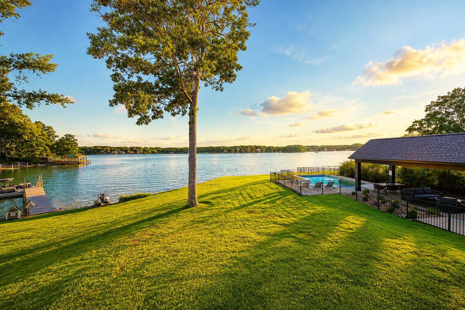 A lakeside property with a swimming pool, a covered patio, and a dock.