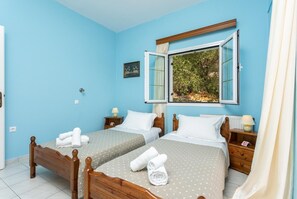Ein Schlafzimmer mit zwei Betten, einem großen Fenster mit freiem Ausblick und einem kleinen Bild an der Wand.