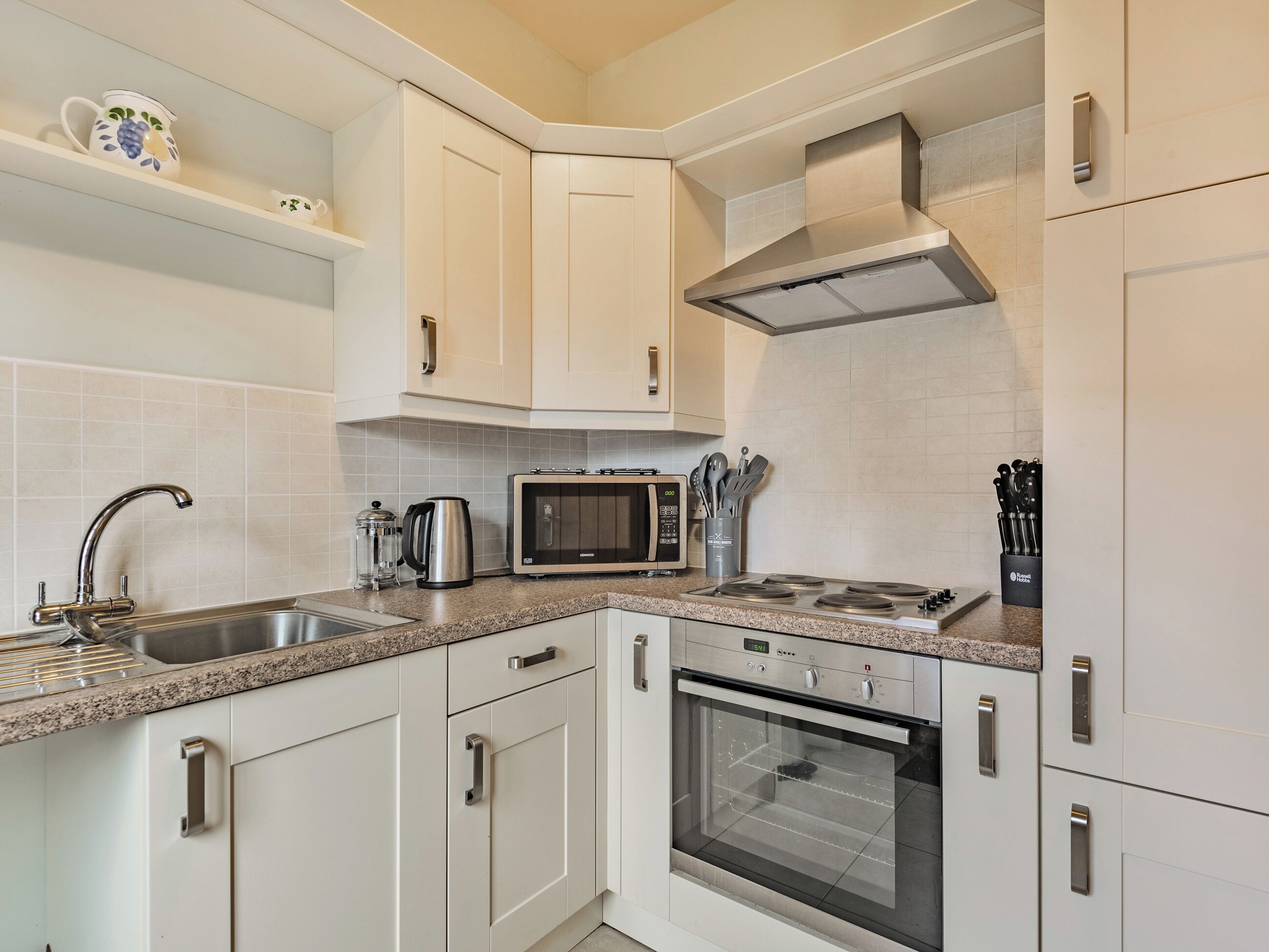 Una cocina moderna con armarios blancos, una estufa de acero inoxidable, un microondas y un horno.