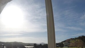 Blick durch ein Fenster auf einen klaren Himmel und ferne Hügel.