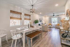 A spacious living area with a dining table, white chairs, a bench, and a sofa set. - Dogs Welcome+Extended Stay+Charming Home Near Dickies+KING Bed+Fully Furnished (Fort Worth)