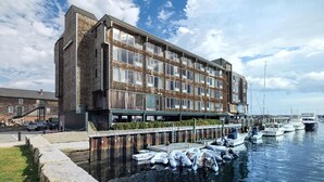 Un bâtiment moderne avec une façade en briques, de grandes fenêtres et un quai où sont amarrés des bateaux.
