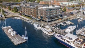 Un port de plaisance avec des bateaux amarrés, un immeuble à plusieurs étages et une vue sur le front de mer.