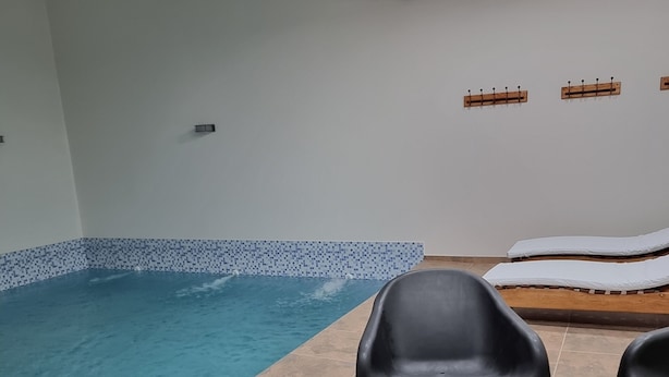 A swimming pool with black plastic chairs and a tiled floor. - Duplex Equipped, with daily cleaning service  (Malargüe)