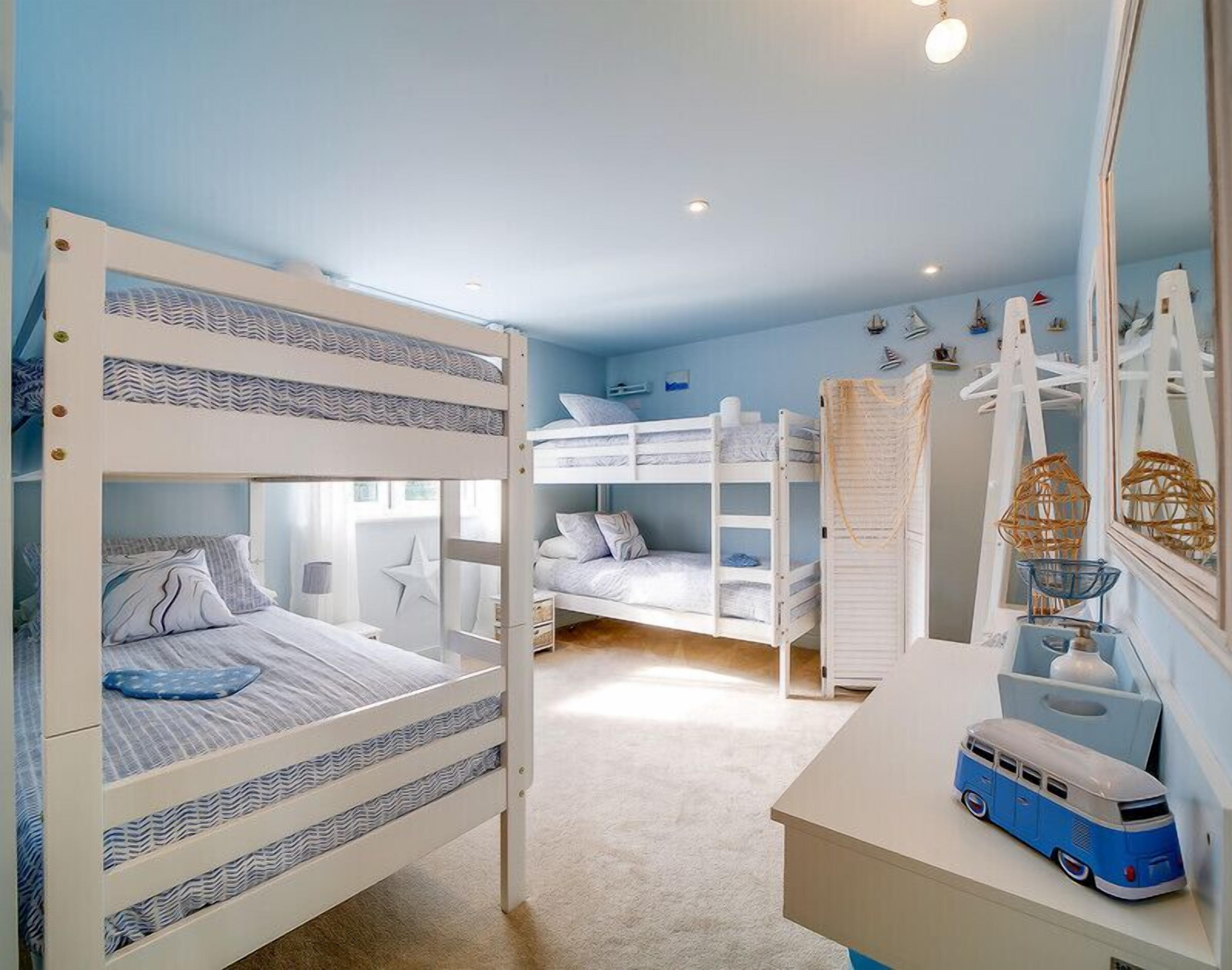 A bunk bed room with a desk and a mirror.