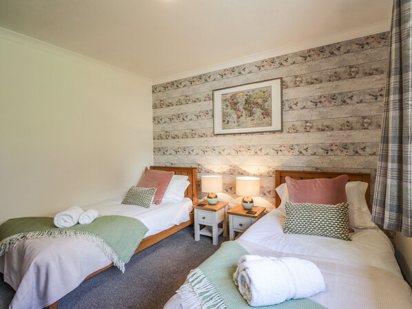 A double room with two beds, each with a pillow, a bedside table with a lamp, and a framed map on the wall. - The Hideout (Portree)