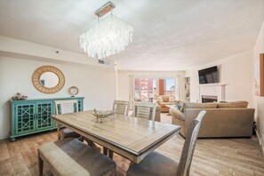 Un coin repas avec une table et des chaises en bois, un buffet turquoise aux portes vitrées, un miroir rond et un lustre.