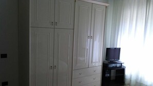 A bedroom with a large wardrobe, a television on a stand, and a bed. - Apartment from helium (La Caletta)