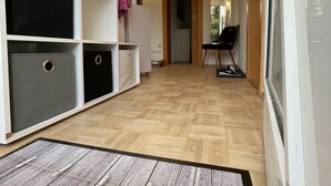Un couloir avec des rangements, une chaise et une porte donnant sur une autre pièce.
