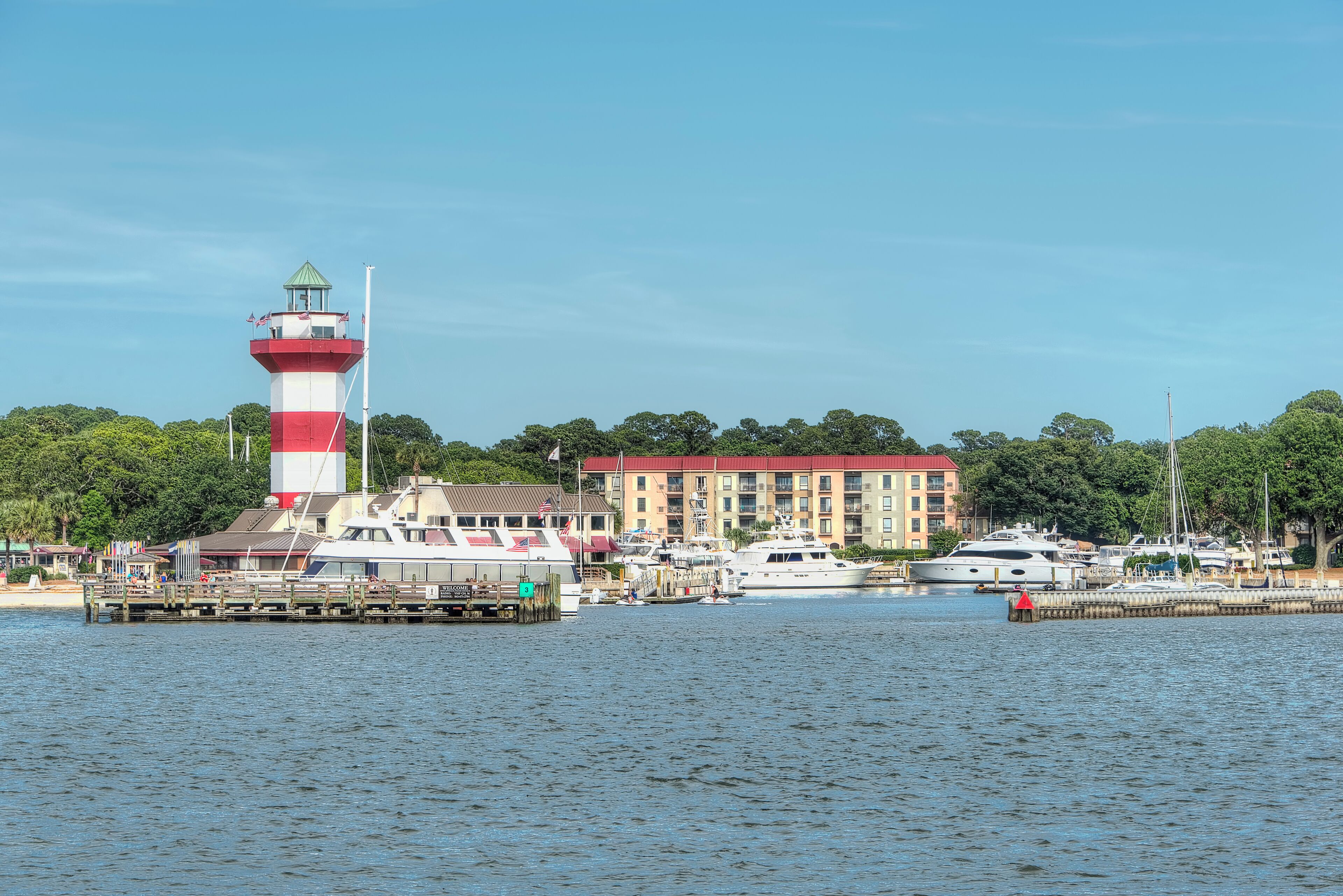 A lighthouse, a marina with boats, and a building with a red roof.